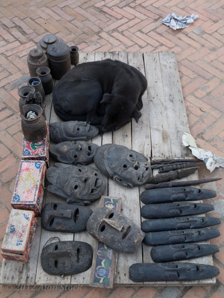 A dog sleeps next to souvenir masks at the Durbar Square